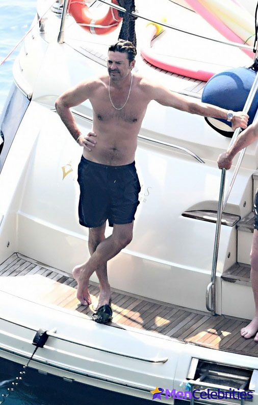 Karl Urban shows off his naked torso while riding a boat