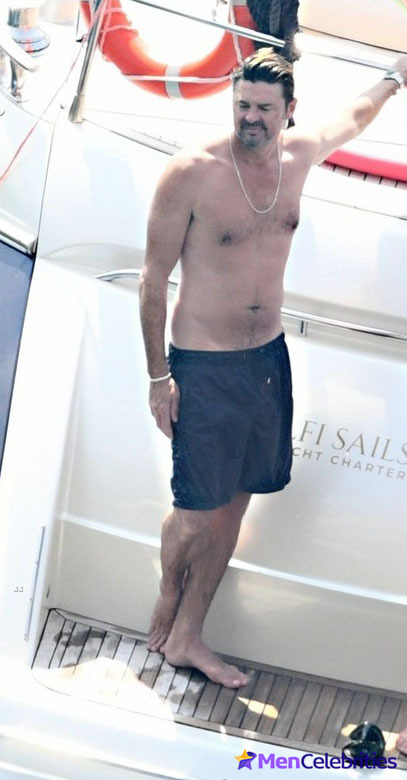 Karl Urban shows off his naked torso while riding a boat