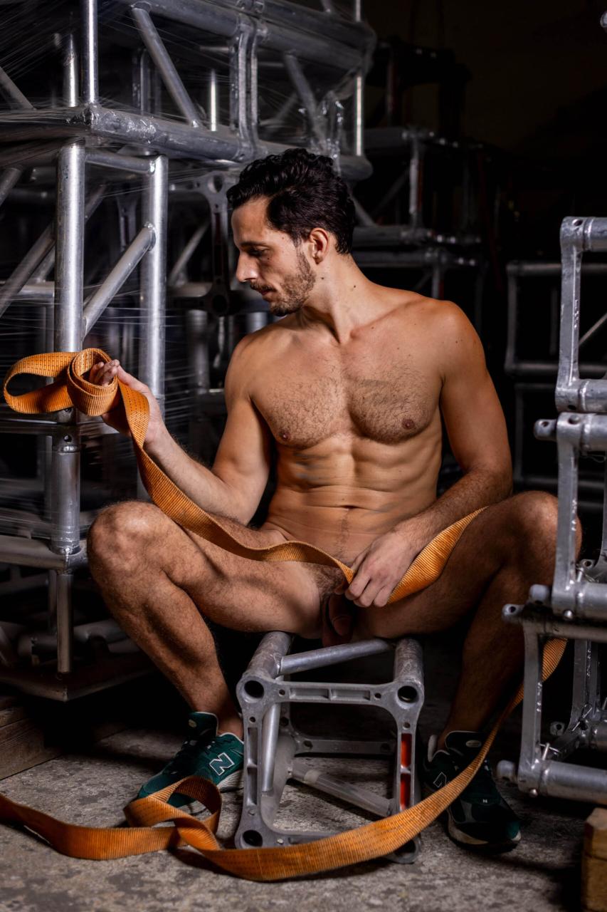 Kiki: the handsome dark-haired curly guy posing nude in a warehouse